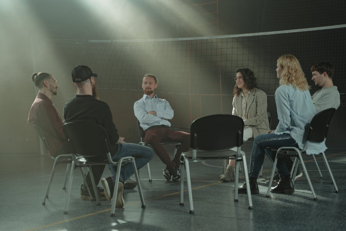 Group therapy session with diverse participants supporting each other in recovery