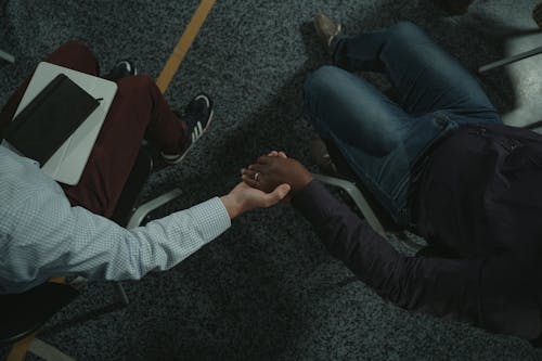 People Sitting on Black and Gray Chair while Holding Hands