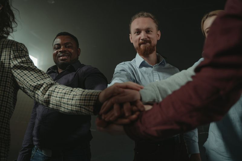 Diverse group of adults forming a team huddle, symbolizing unity and collaboration.
