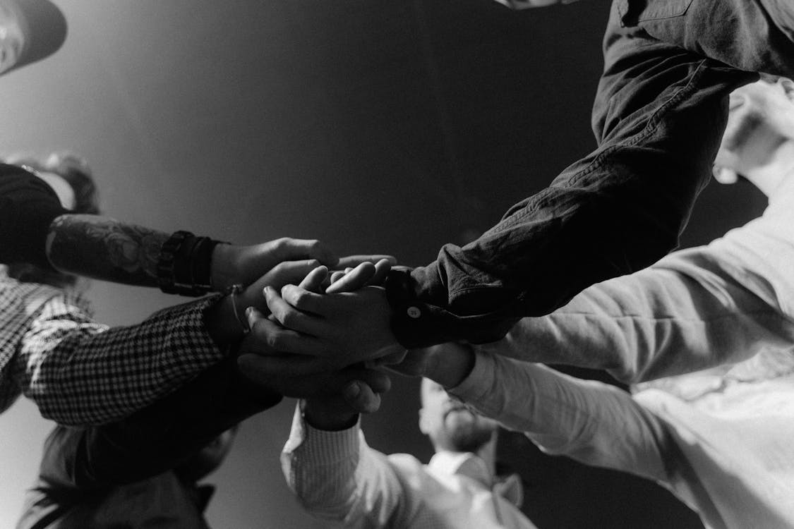A diverse group of individuals standing in a circle, holding hands, symbolizing unity and togetherness.