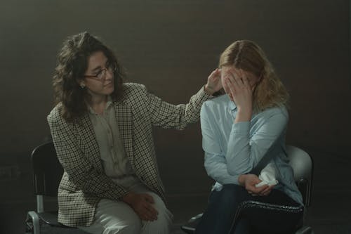 Woman in Brown and White Checkered Blazer Sitting beside Woman in Blue Long Sleeve Shirt