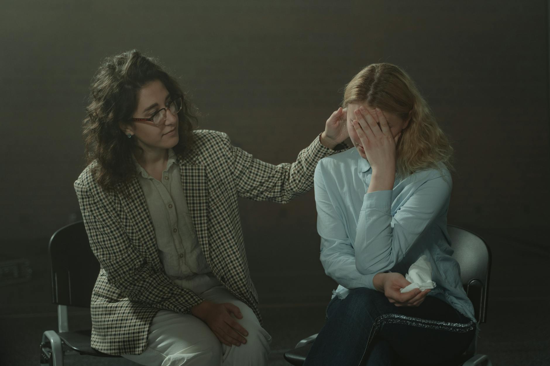 Woman in Brown and White Checkered Blazer Sitting beside Woman in Blue Long Sleeve Shirt