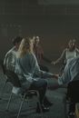 一小群成年人在光线昏暗的房间里手牵着手，举行支持小组会议