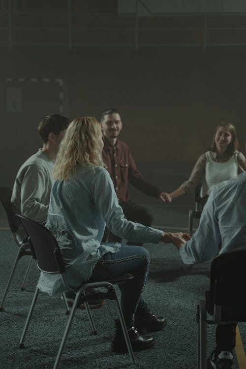 Free Woman in White Long Sleeve Shirt Sitting on Black Chair Stock Photo