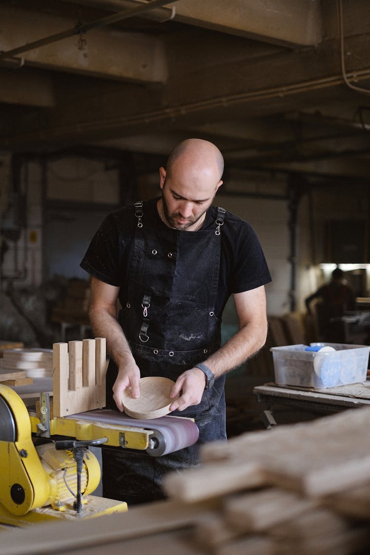 Focused Carpenter Grinding Round Piece Of Wood