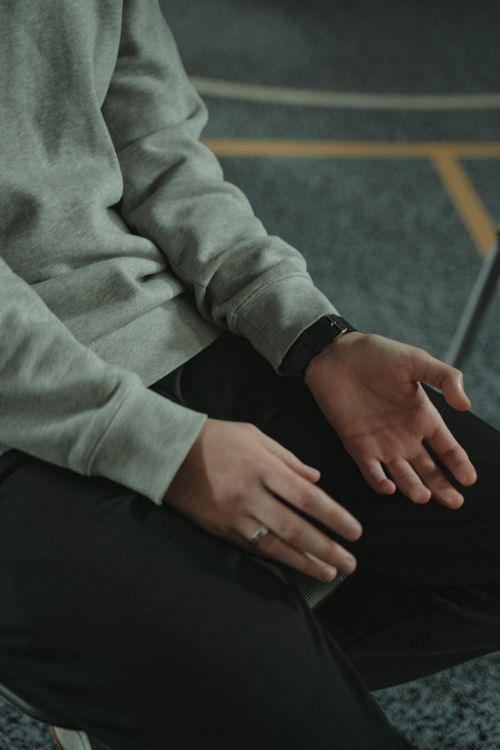 Free Person's hands resting thoughtfully on lap, expressing contemplation. Stock Photo