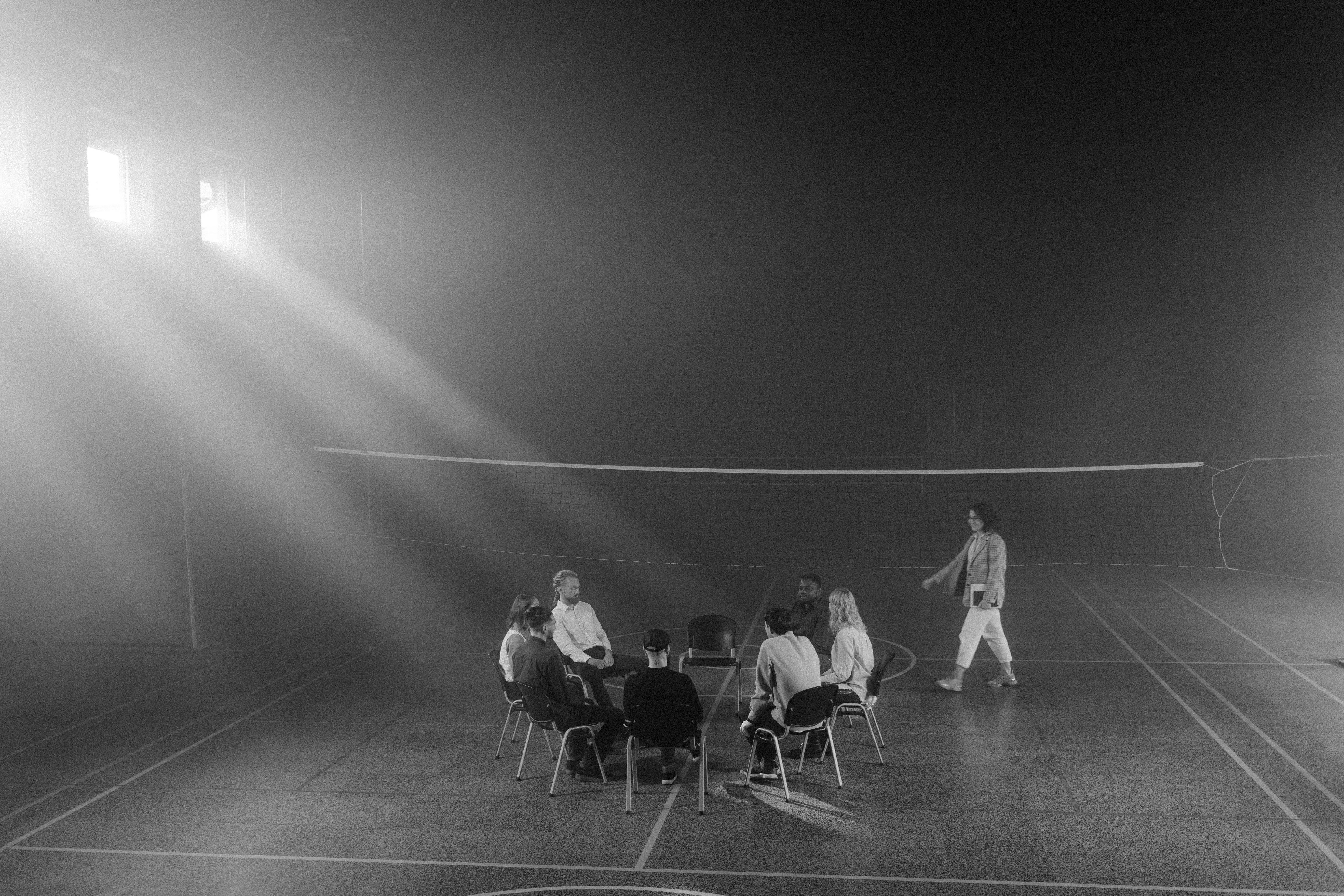 grayscale photo of people sitting on the chairs