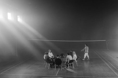 Grayscale Photo of People Sitting on the Chairs