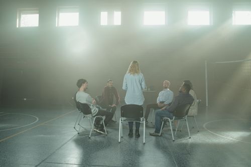 Free A group therapy session with diverse adults seated in a sunlit room. Stock Photo