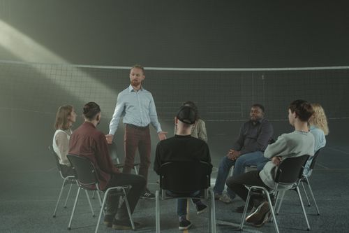 Free A diverse group participating in a therapy session with a facilitator indoors. Stock Photo