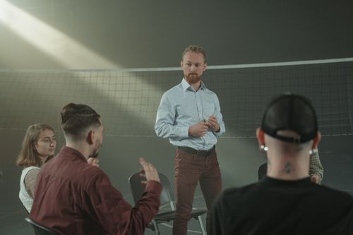 Free Four people engaged in a group discussion inside a room with a net background. Stock Photo
