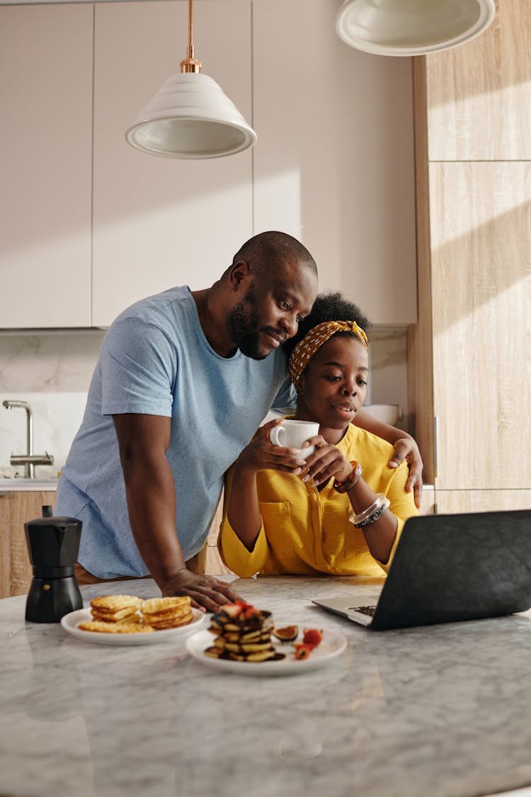 Man And Woman Looking At A Laptop Together While In Breakfast