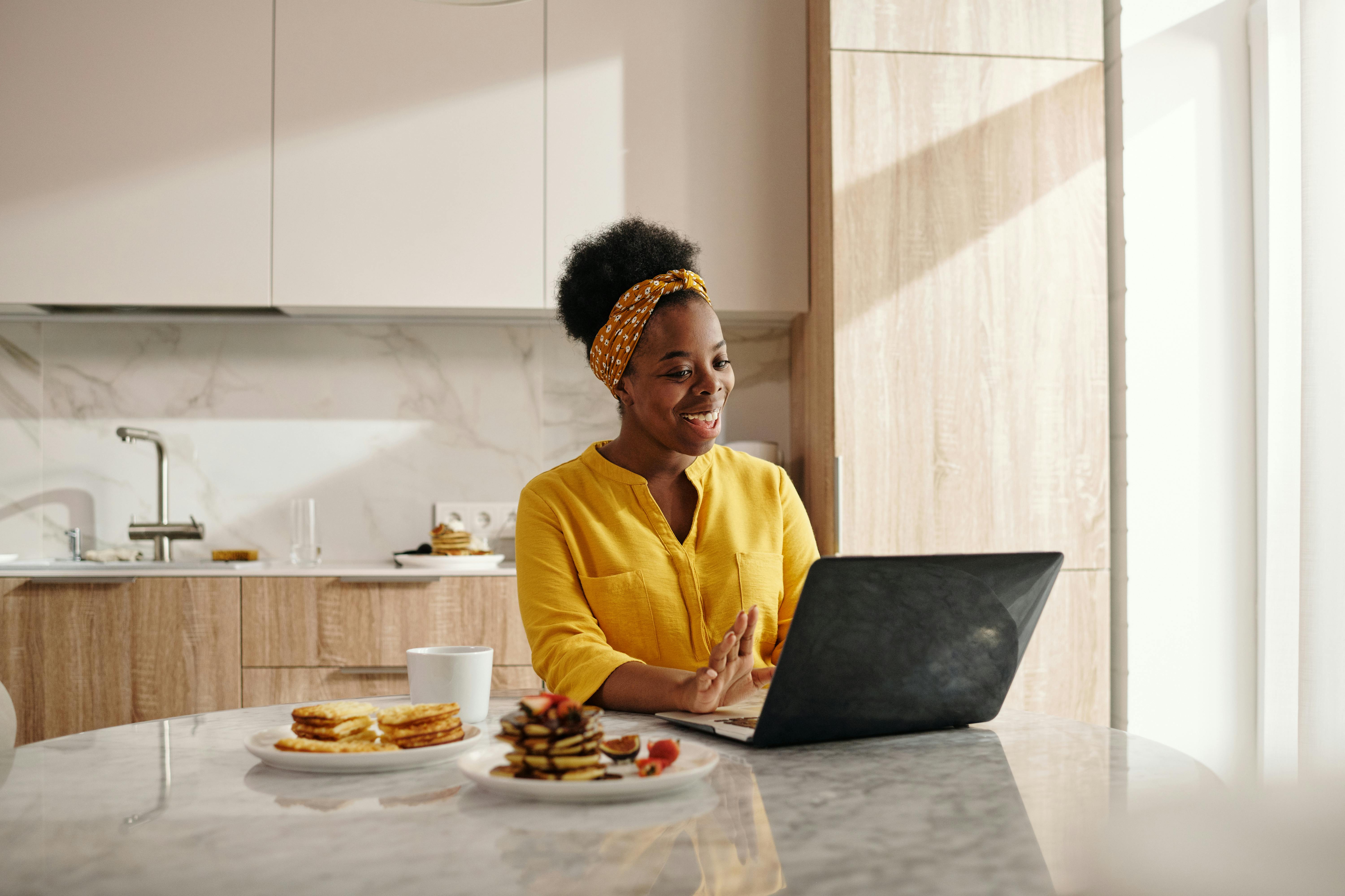 happy woman in yellow top using a laptop