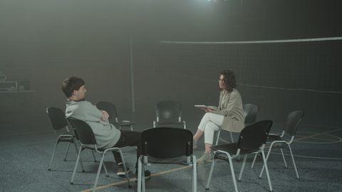 A one-on-one therapy session taking place indoors in a gymnasium setting.