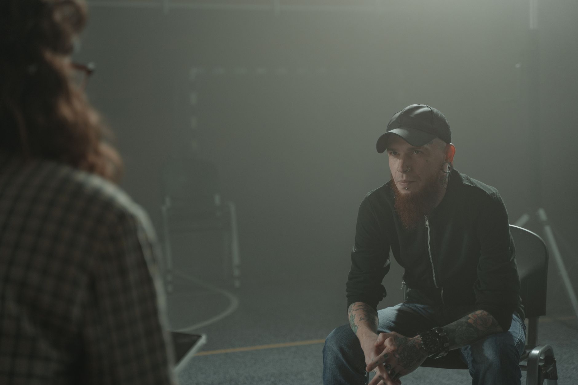 A bearded man with tattoos in a one-on-one counseling session indoors.