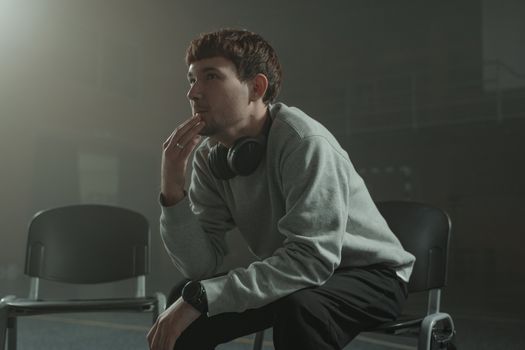一位成年男子在室内沉思，他戴着耳机，姿态放松