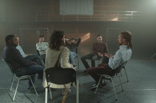 Free A diverse group engages in a therapy session inside a gym, fostering mental health support. Stock Photo