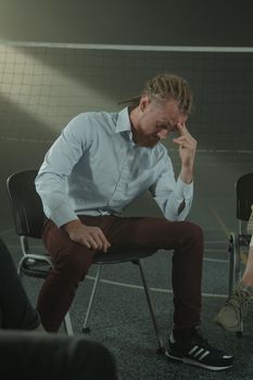 一名扎着辫子的男子正参加一场专注于心理健康和支持的团体治疗