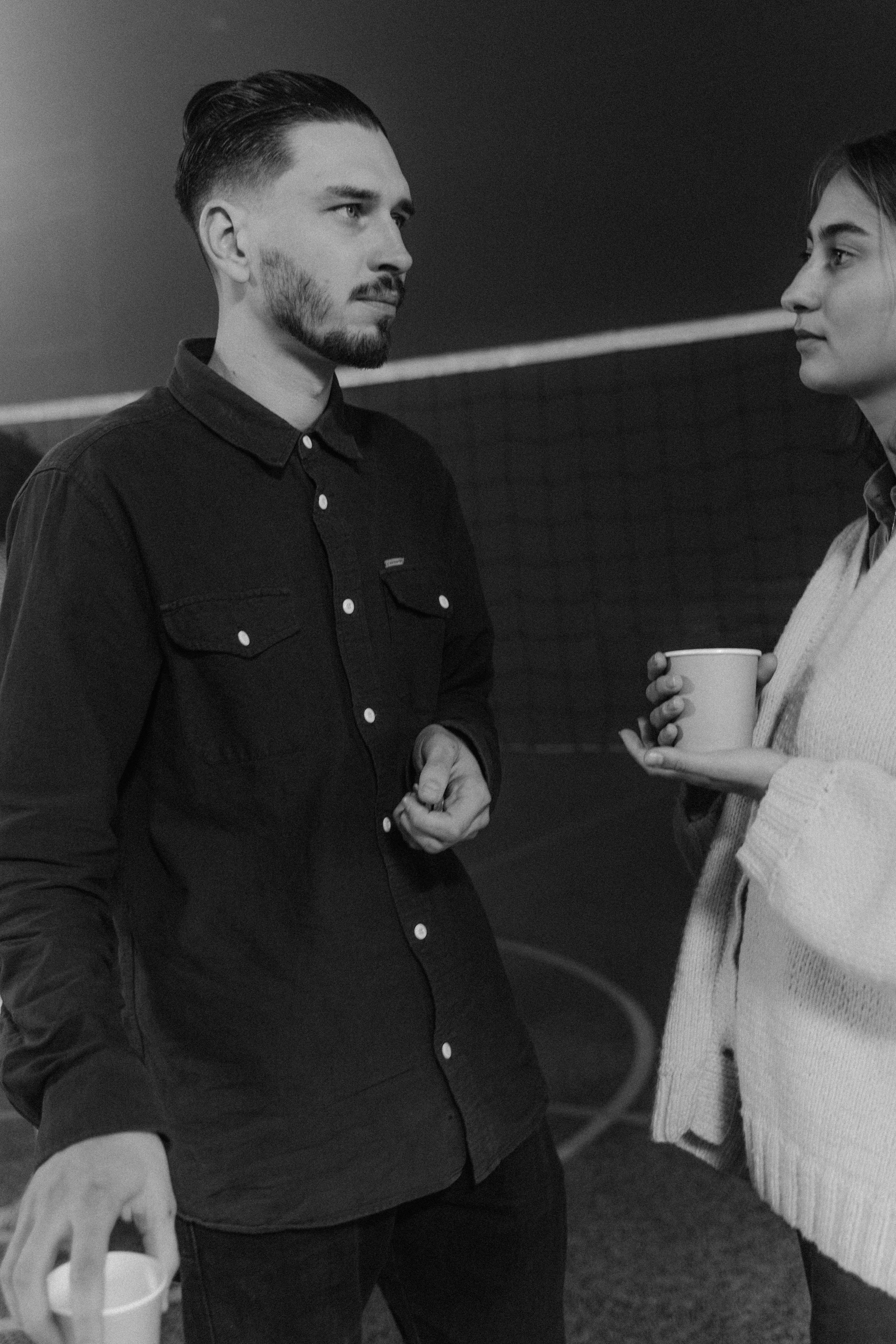 man in black button up shirt holding white ceramic mug