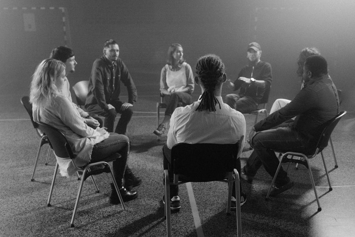 Diverse group of people sitting in circle during support group meeting