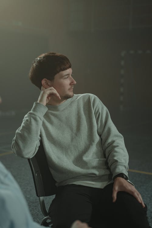 Man in Gray Sweater Sitting on Black Chair