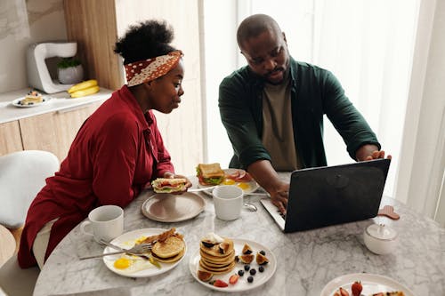 Free Man and Woman Looking at the Laptop While in Breakfast Stock Photo