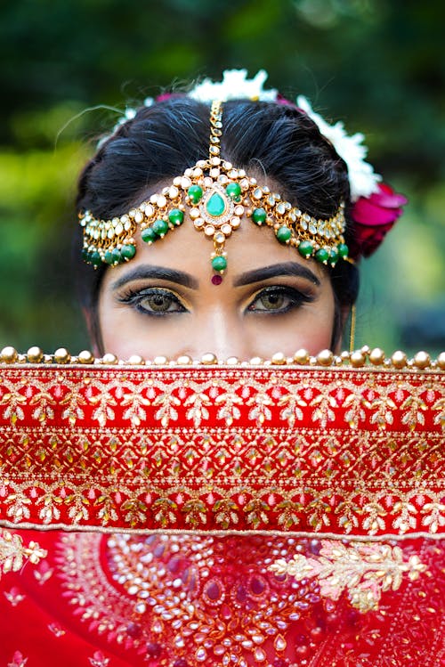 Woman With Makeup and Head Accessories Behind Red Scarf 