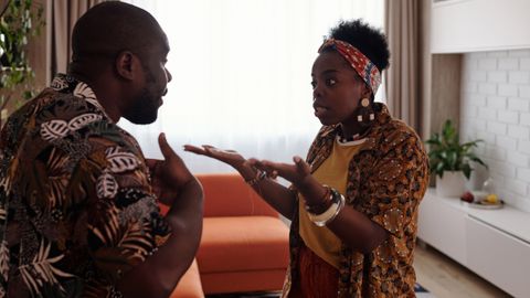A couple arguing passionately in their living room, expressing emotions and gestures.