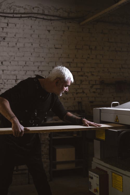 Middle aged man working with timber plank and lathe
