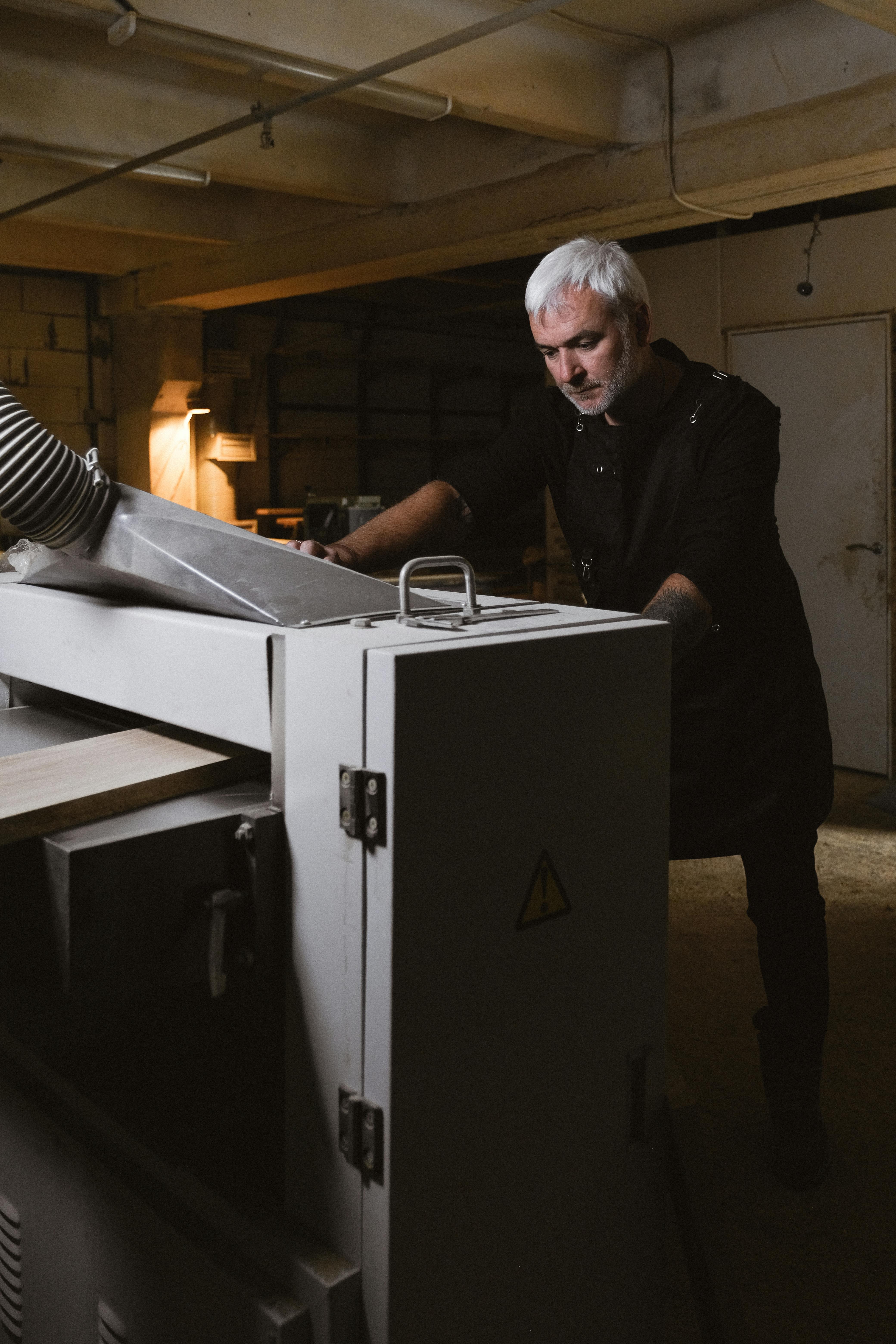 middle aged man installing turning machine in workshop