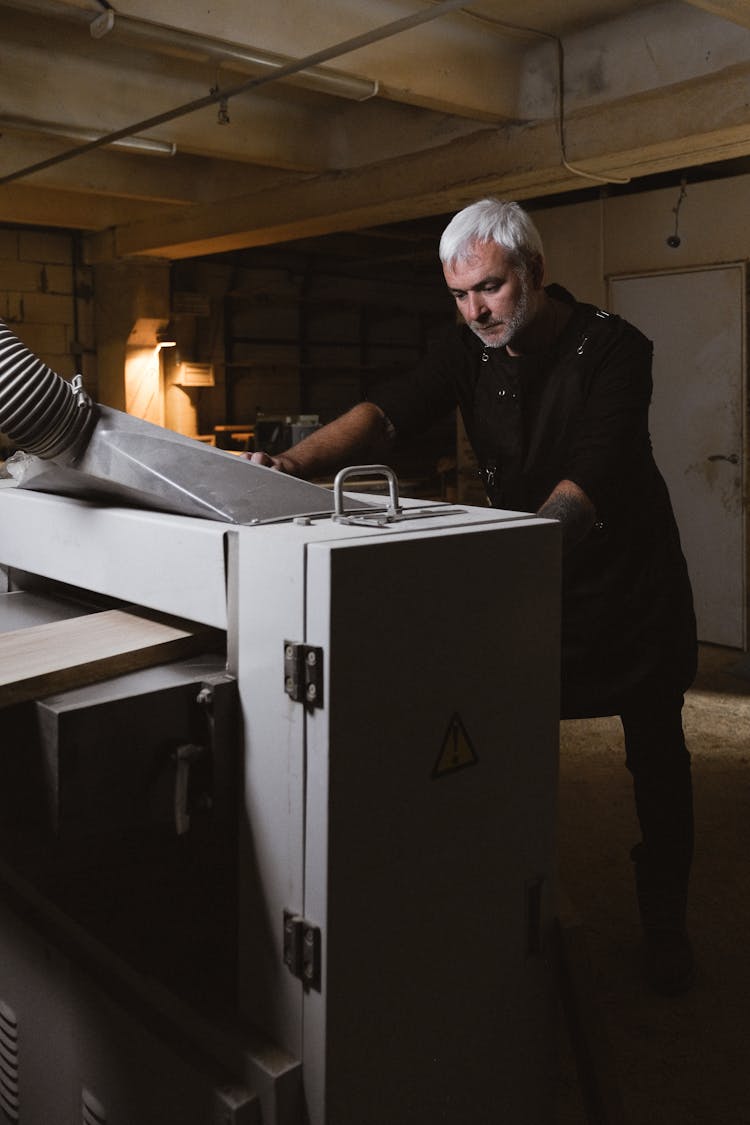 Middle Aged Man Installing Turning Machine In Workshop