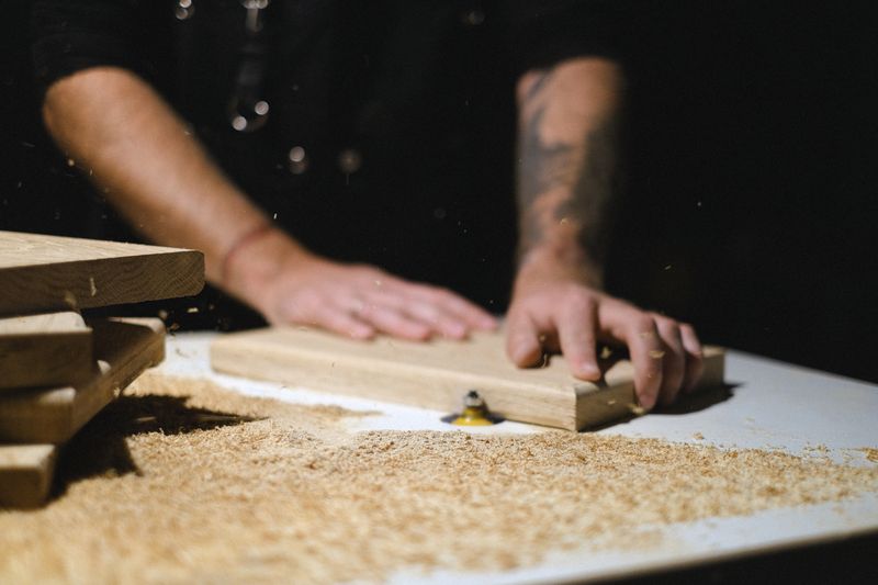 Artesano trabajando madera en taller con herramientas manuales