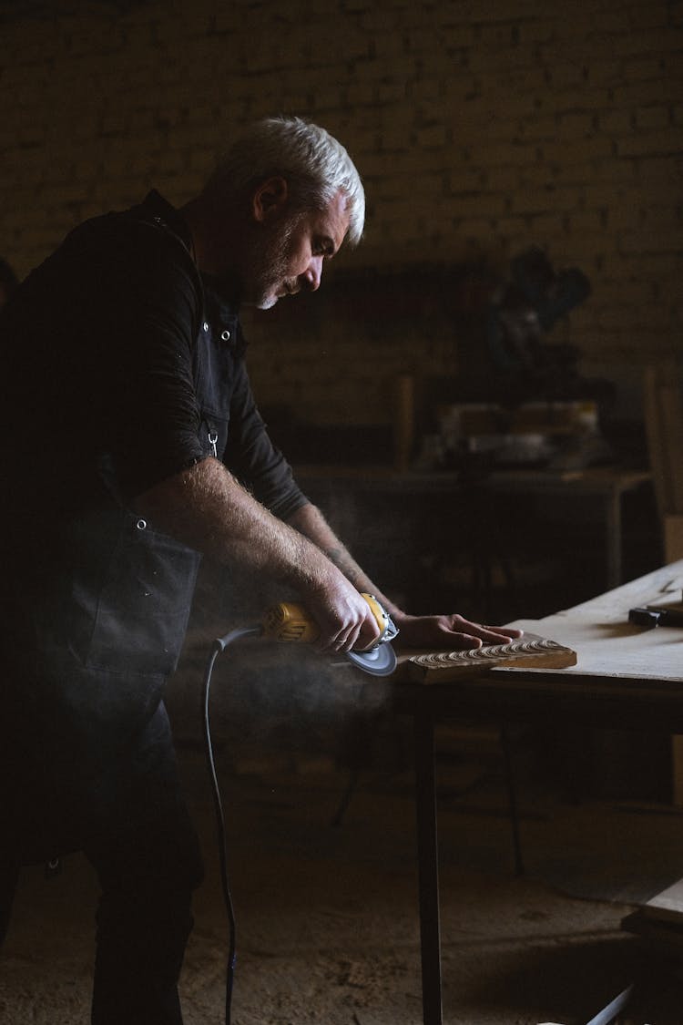 Focused Craftsman Working With Angle Grinder In Carpentry