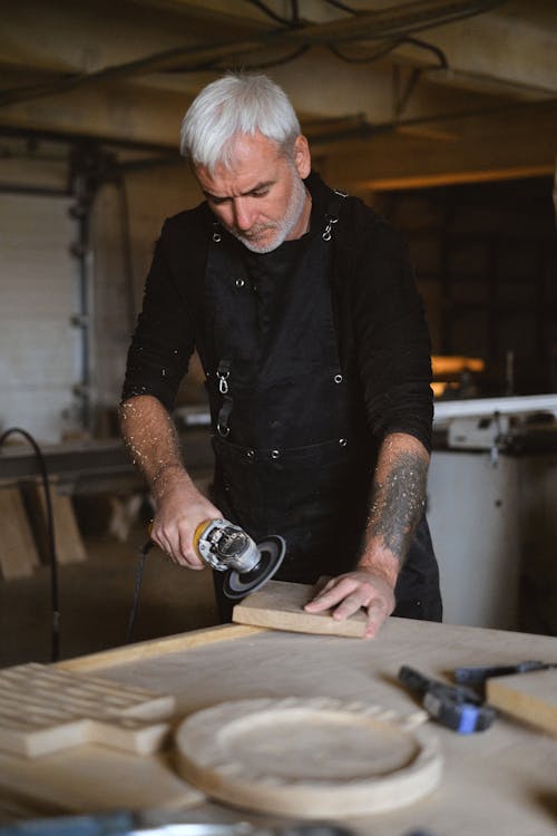 Skilled woodworker grinding wooden detail