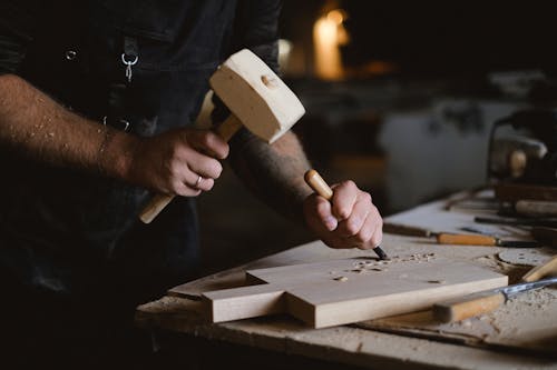 Crop woodworker making patterns on wooden board