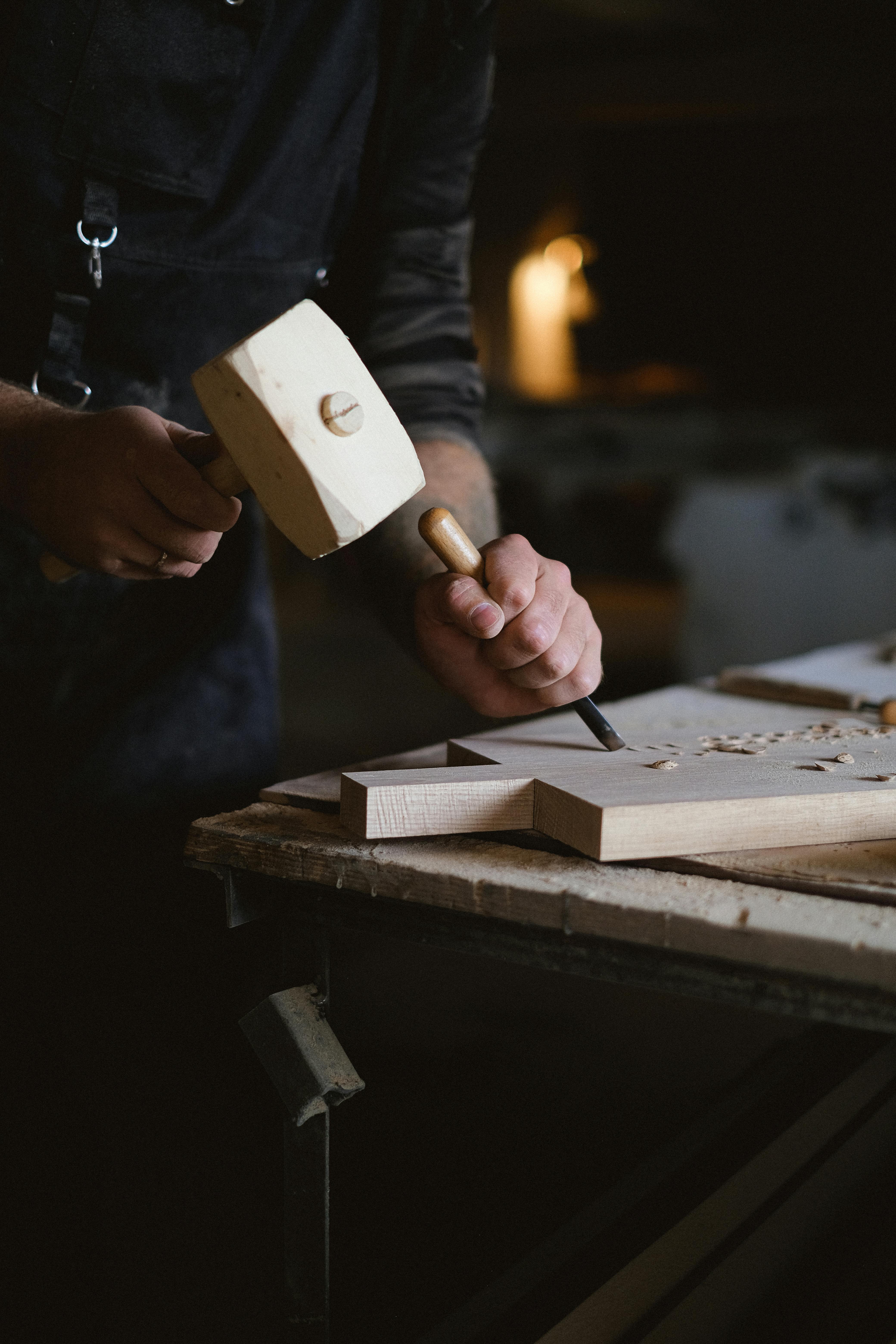 professional craftsman with wood mallet carving piece of wood