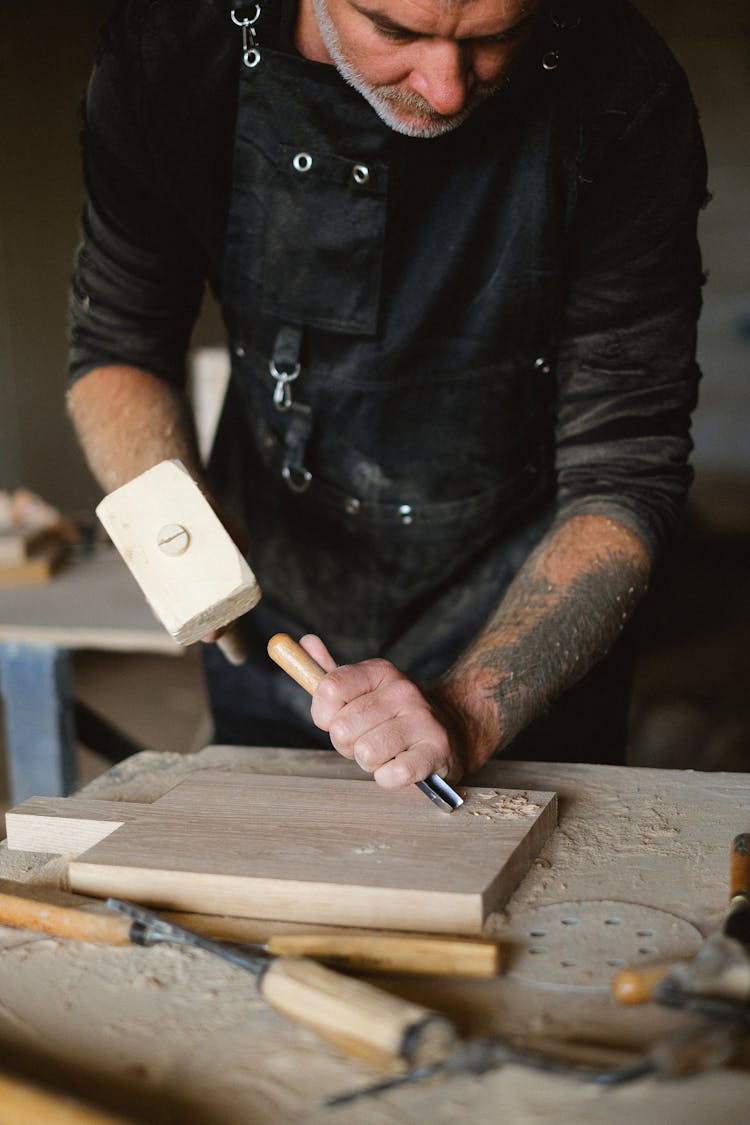 Crop Craftsman Creating Pattern On Wooden Board With Chisel