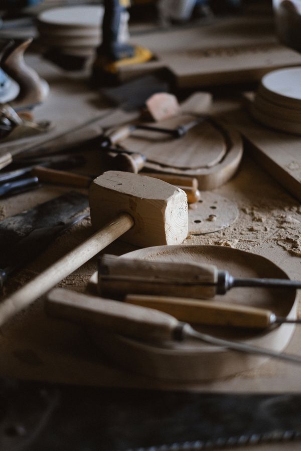 Wooden mallet, chisels and hand tools resting on a carpentry bench covered in wood shavings