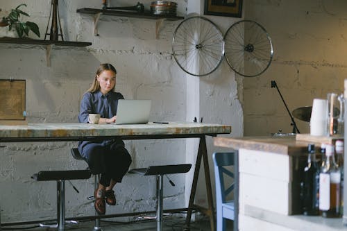 Free Woman working remotely on laptop with coffee cup in loft Stock Photo