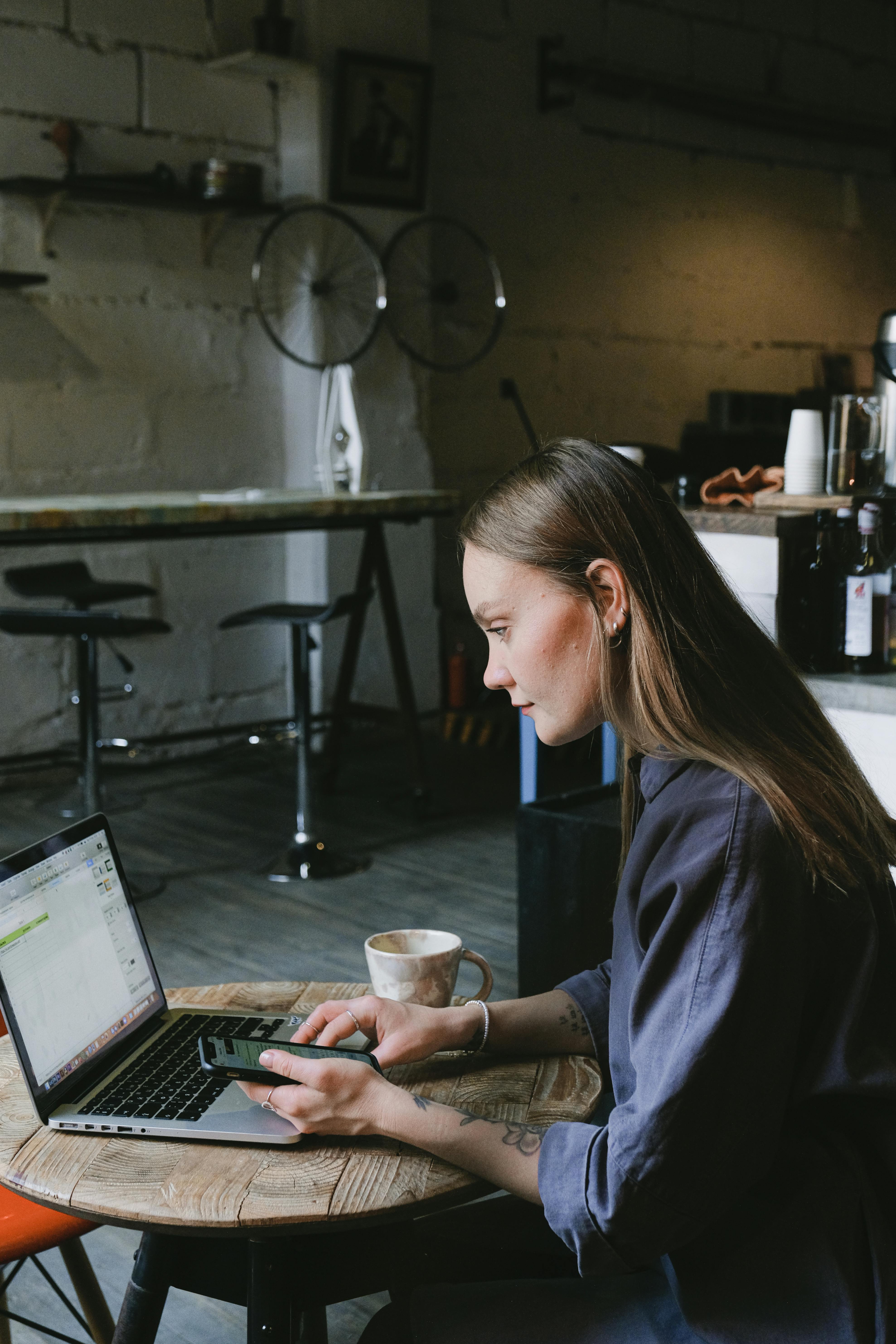 serious young businesswoman using laptop in creative cafe