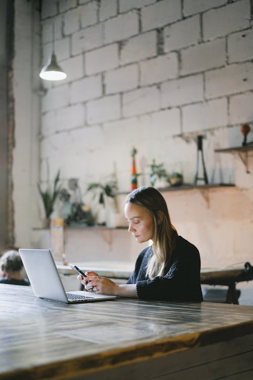 Thoughtful woman text messaging on smartphone at counter