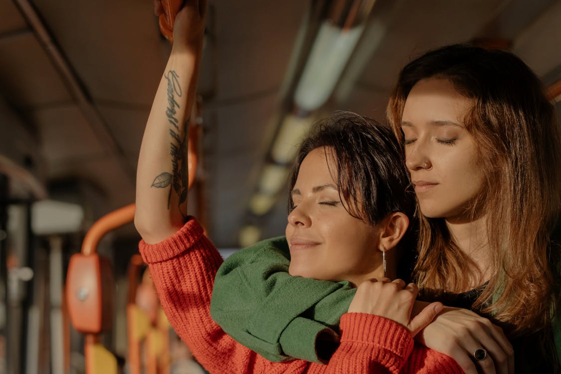 Free Women Hugging While Standing in a Train Stock Photo
