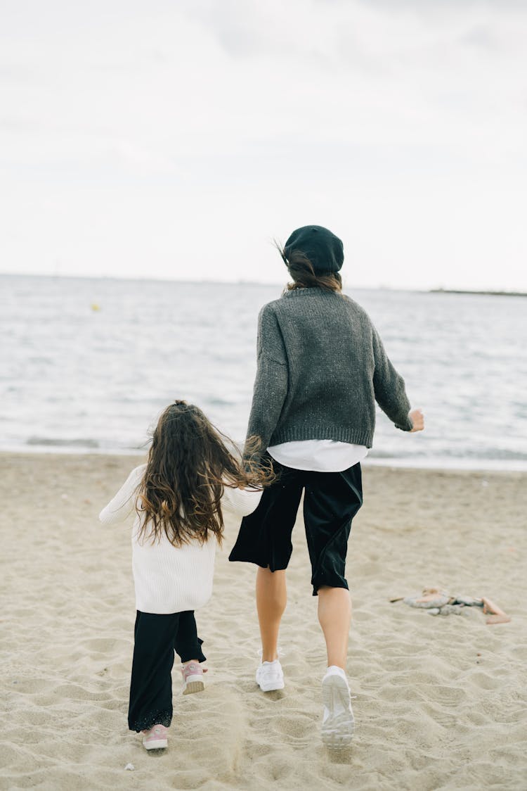 Woman And Child Running On Beach Sand