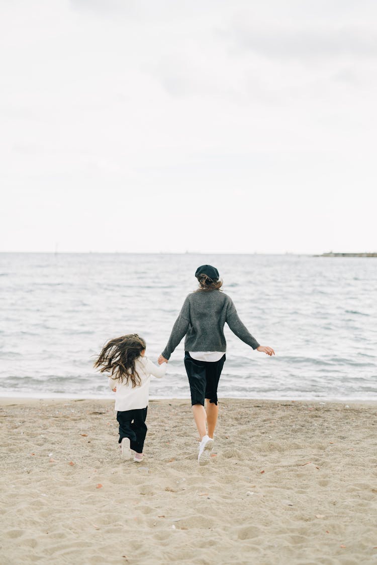 A Woman And Girl Walking On The Beach