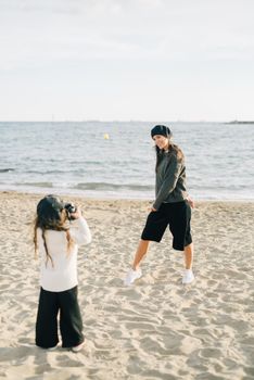 A mother and daughter capturing memories on a sunny beach day.