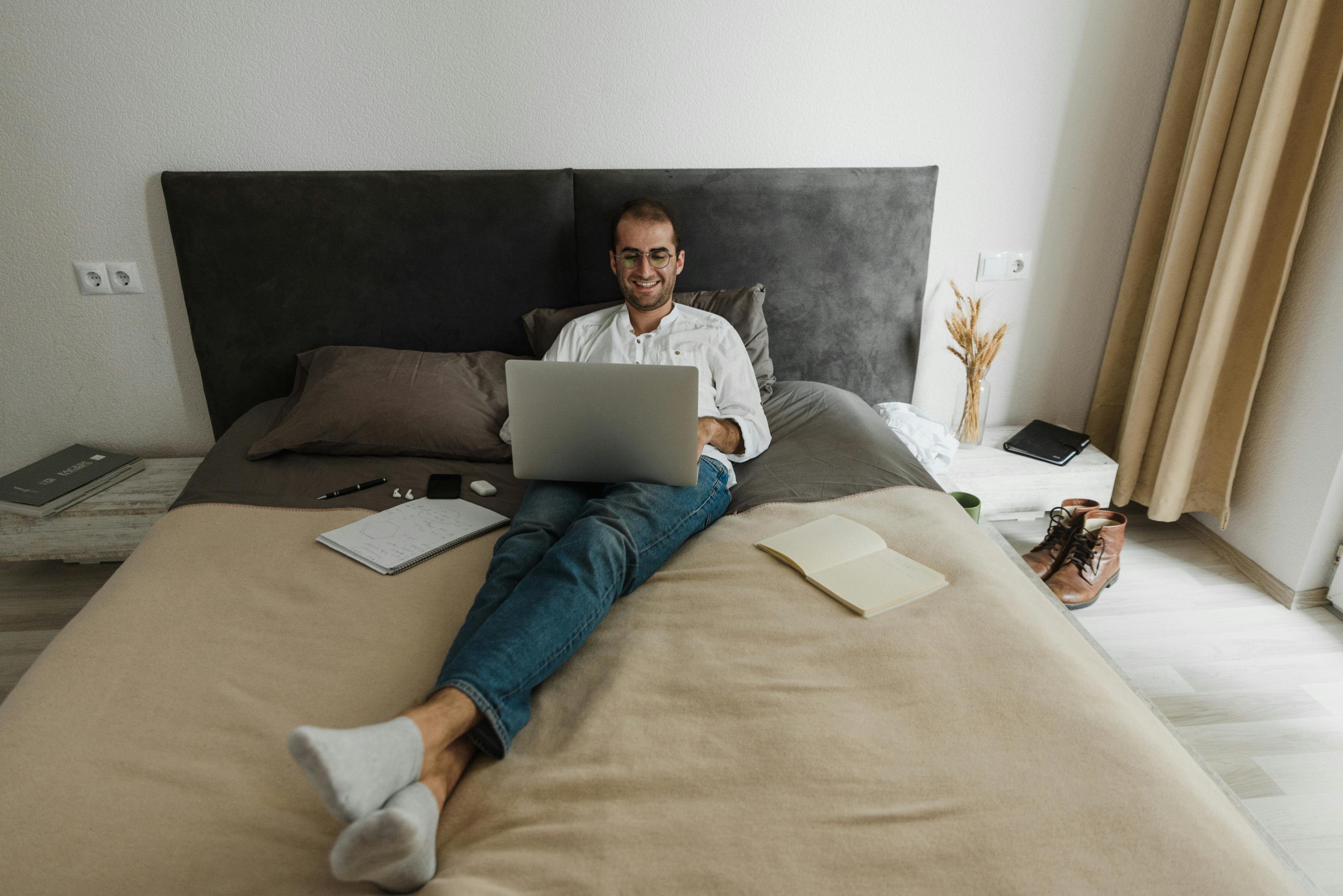 man in gray shirt and blue denim jeans lying on bed