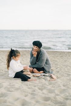 一个女人和孩子在沙滩上堆着石头