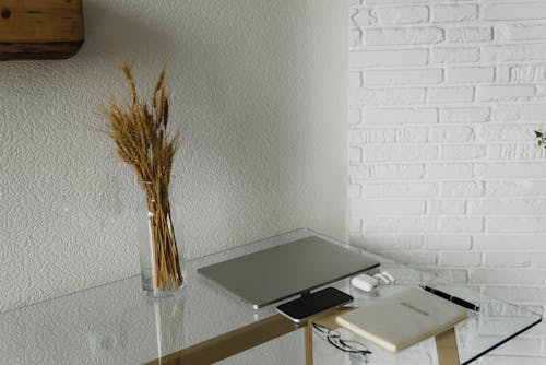 Electronic Gadgets  on a Glass Desk with Notebook and Pen