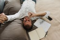 Man in White Button Up Shirt Lying on Bed