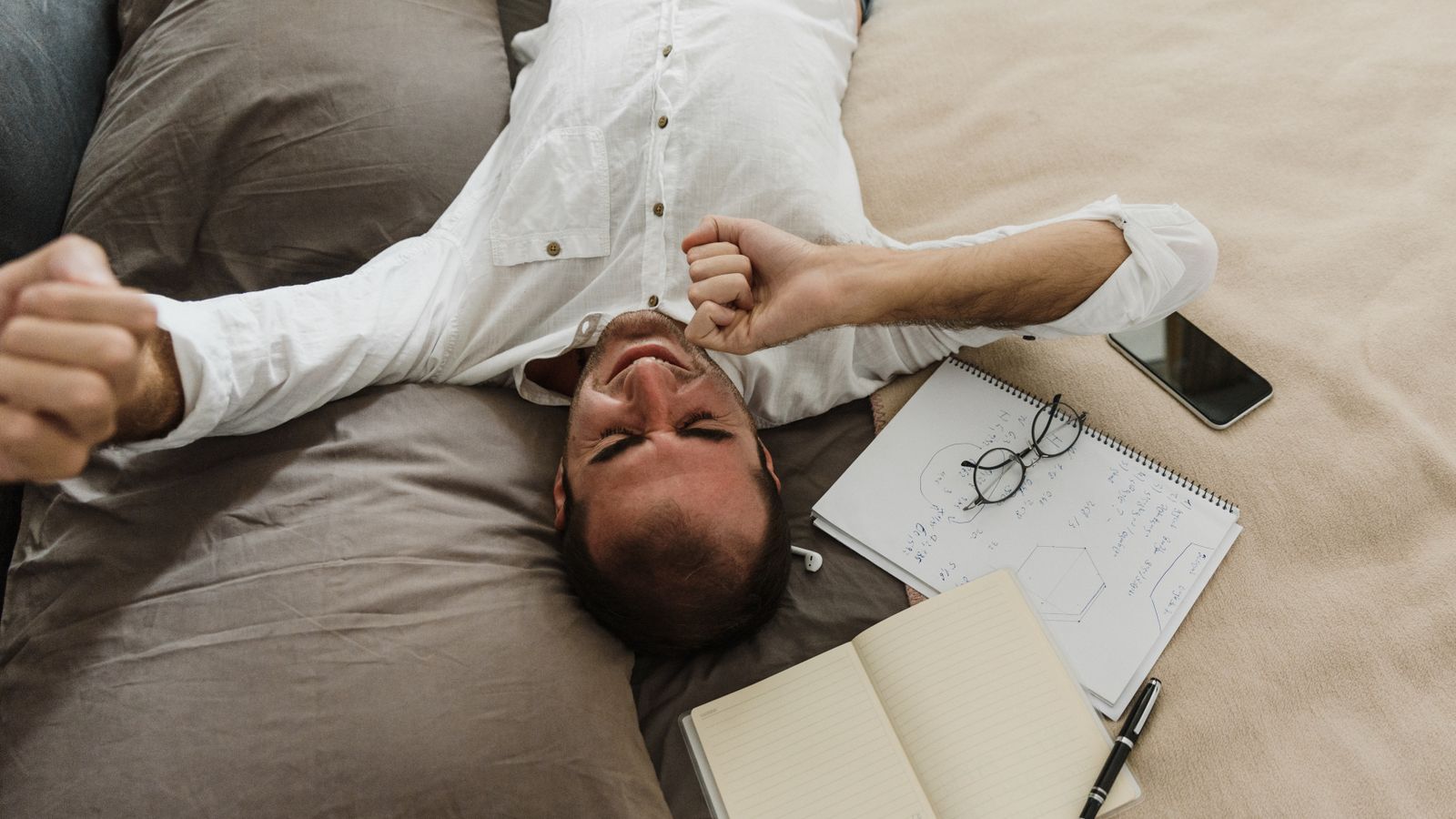 Tired man stretching on a bed